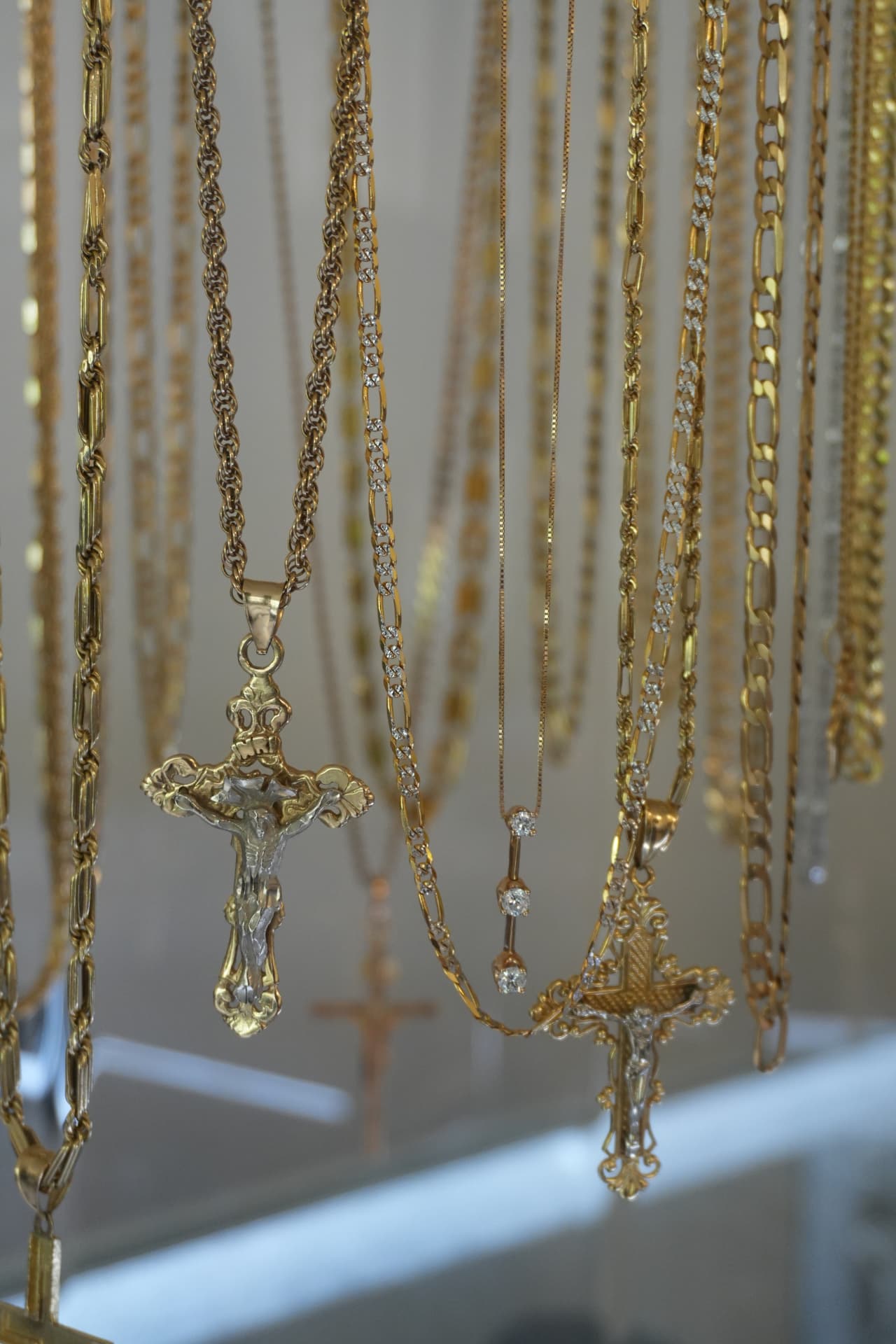 Gold crucifix pendants and chains hanging in the display case