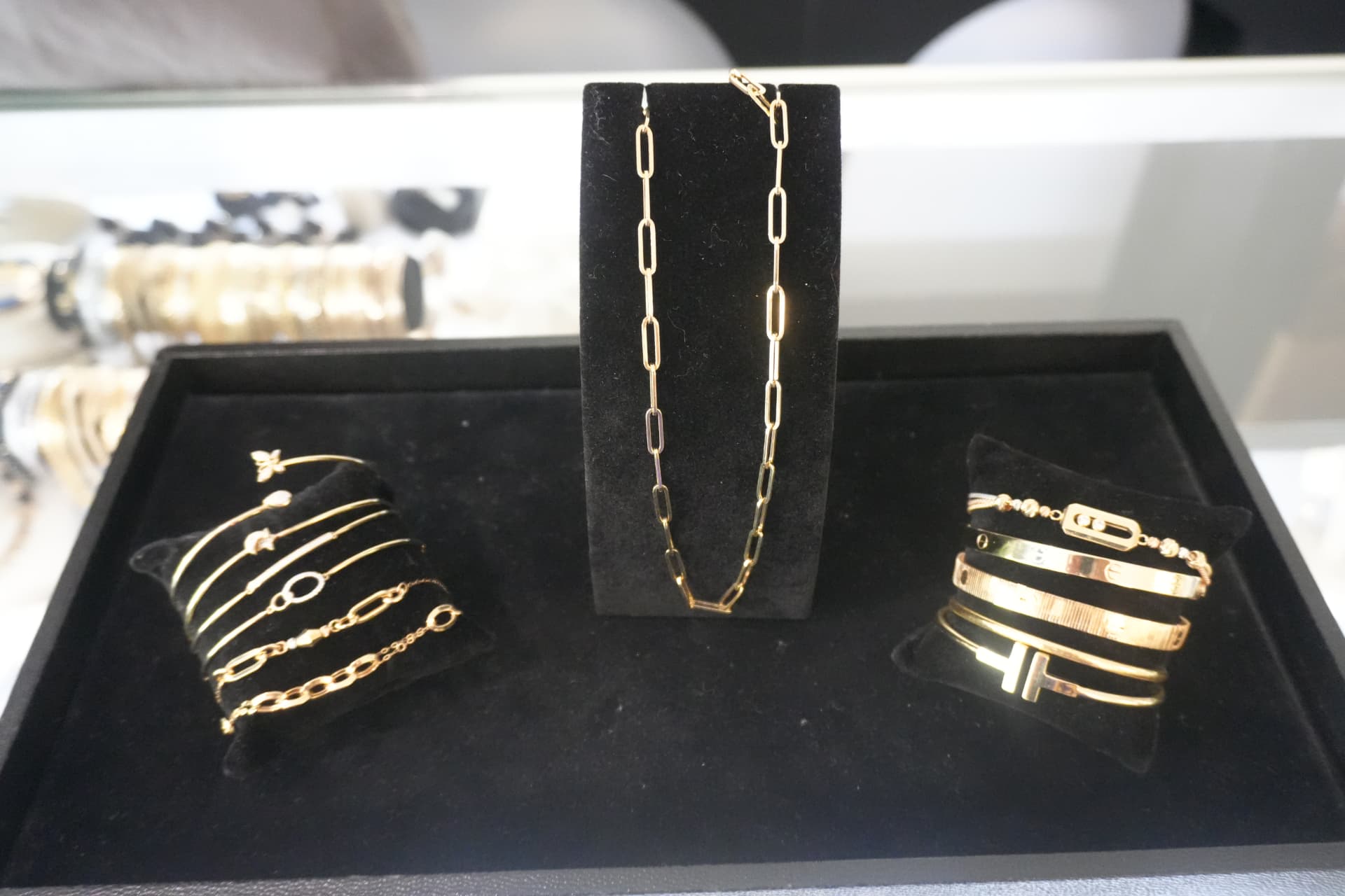 Gold bangles, a paperclip chain and cuff bracelets in a velvet tray