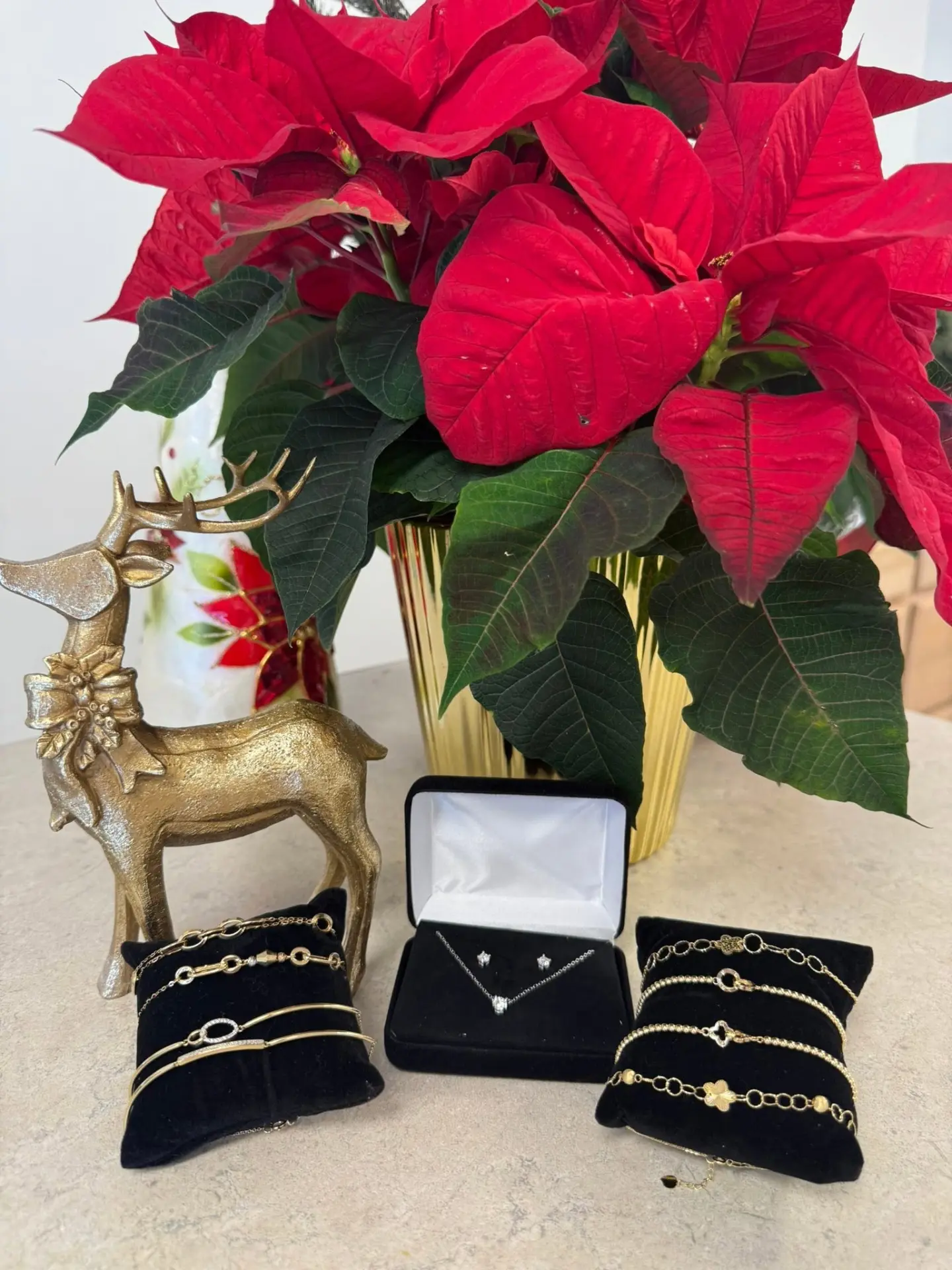 Gold bracelets and a diamond necklace set beside a red poinsettia
