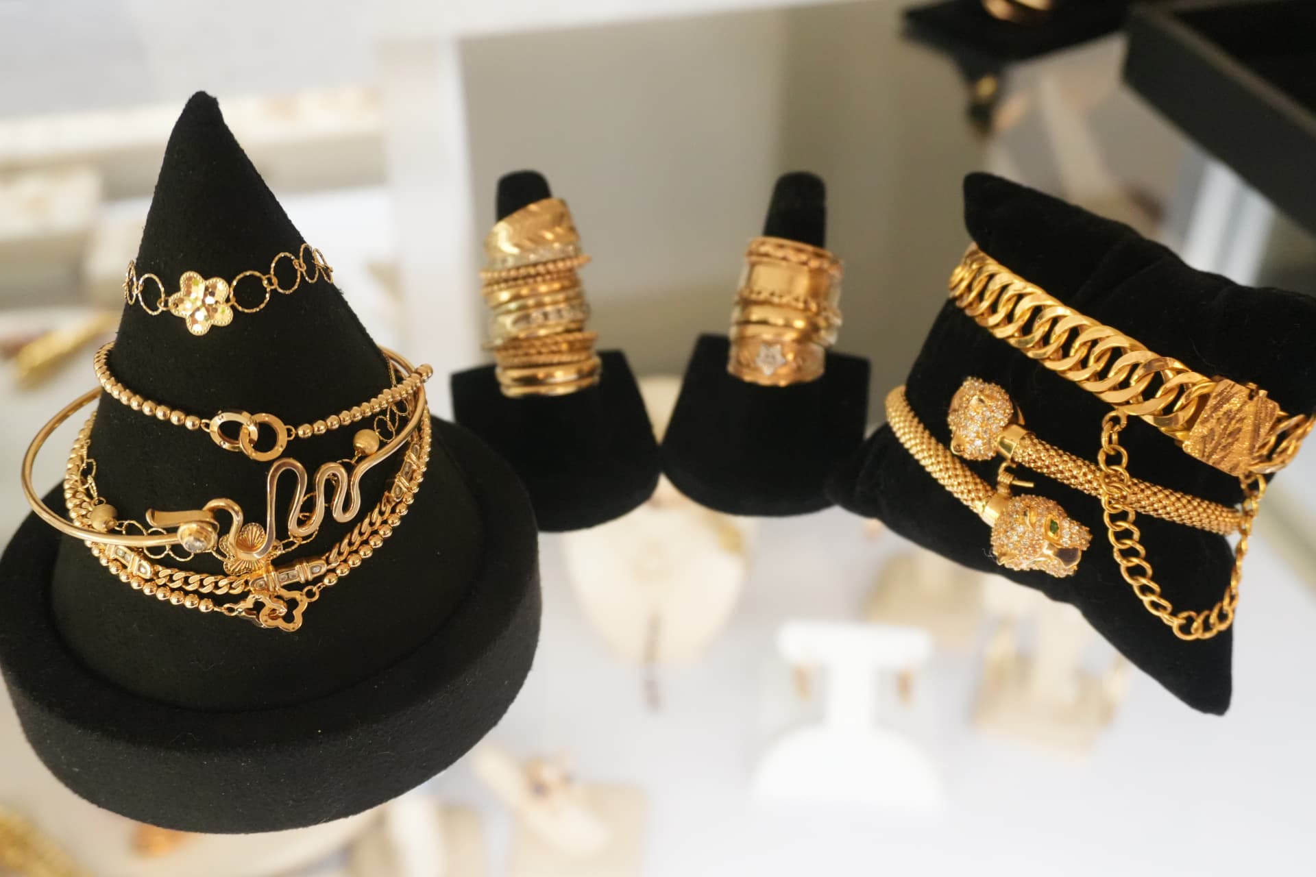 Gold rings and charm bracelets displayed on black velvet stands