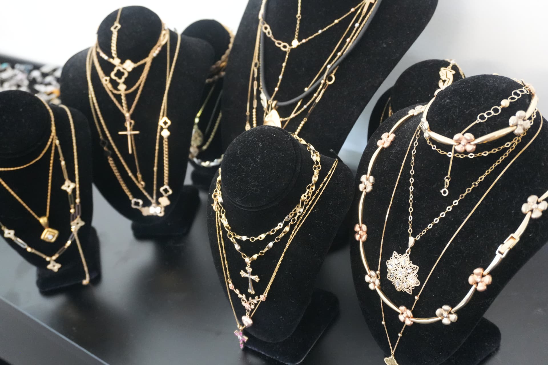 Black velvet busts layered with gold chains, crosses and flower necklaces