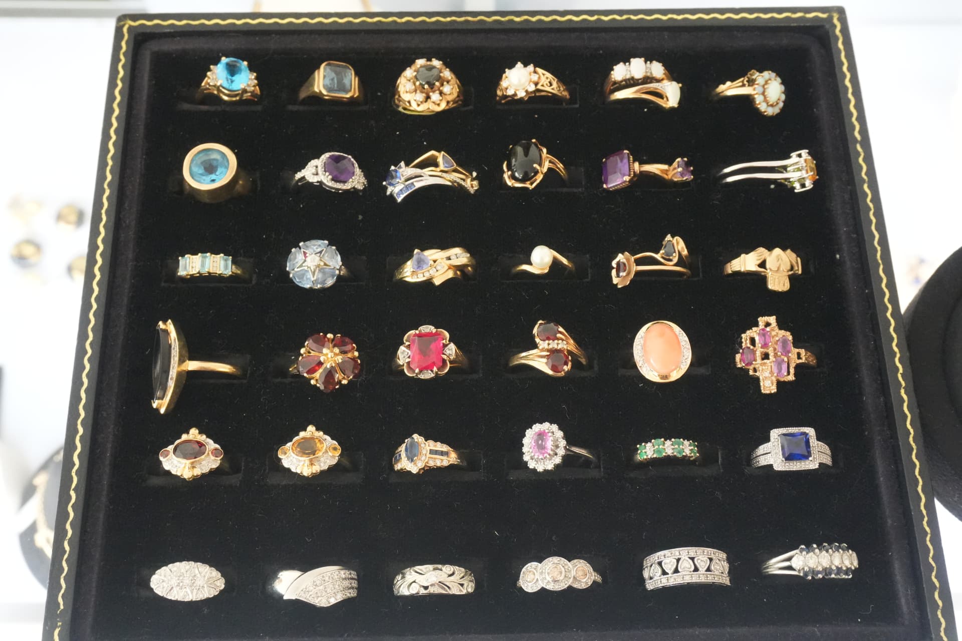 A tray of gemstone rings — topaz, garnet, opal, amethyst and pearl — in gold settings