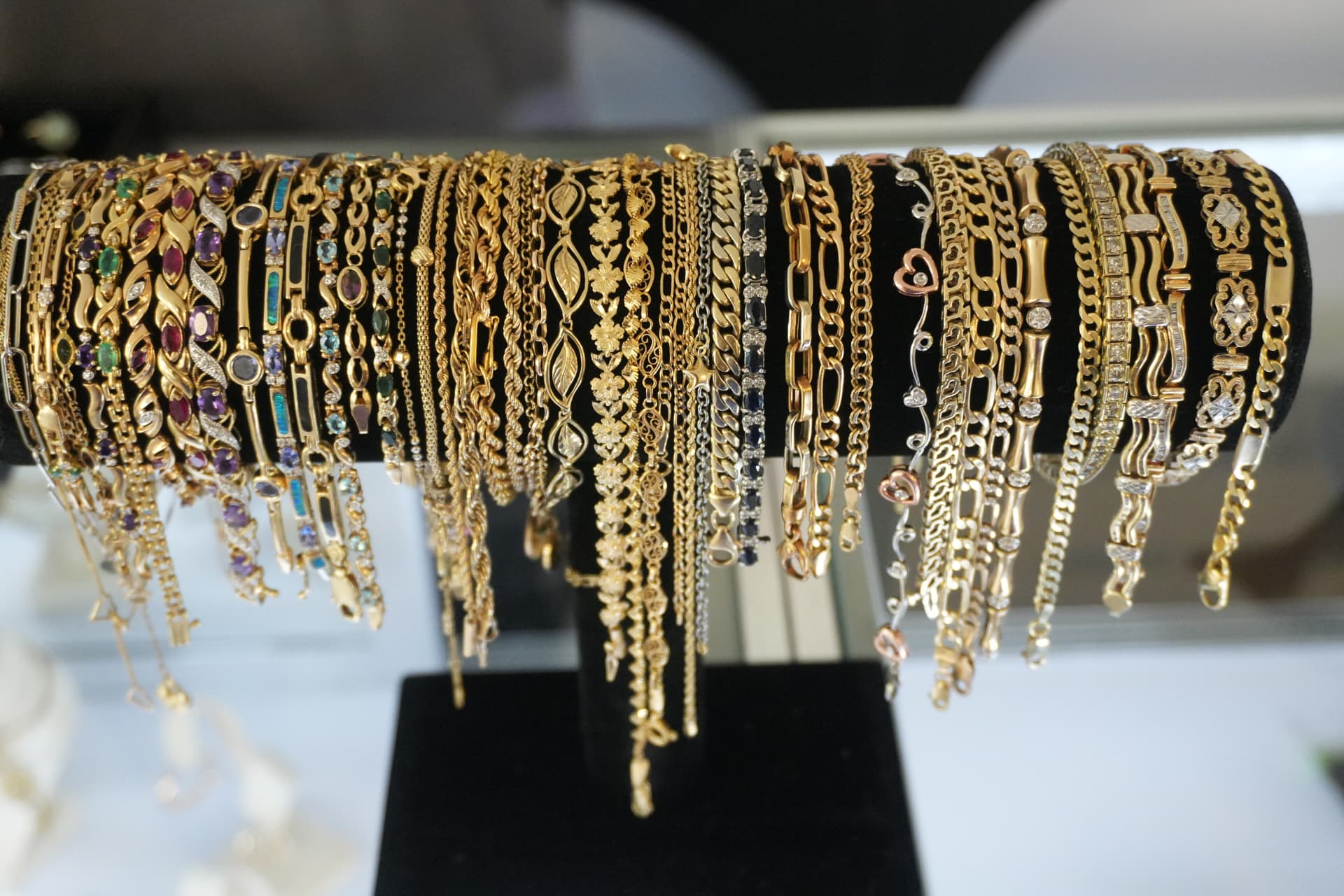 A stand lined with dozens of gold and gemstone bracelets