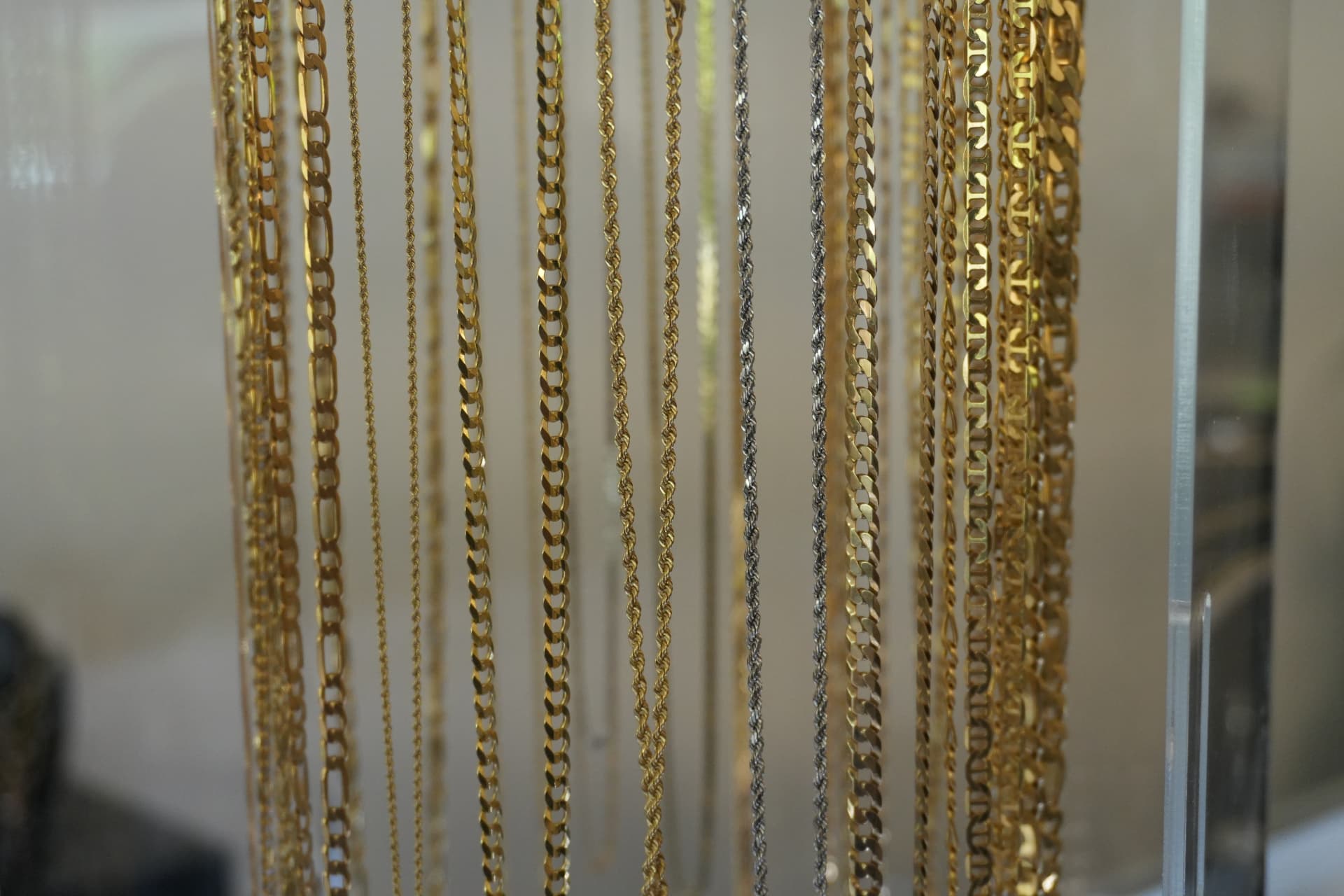 Rows of gold rope, figaro and curb chains hanging in the case