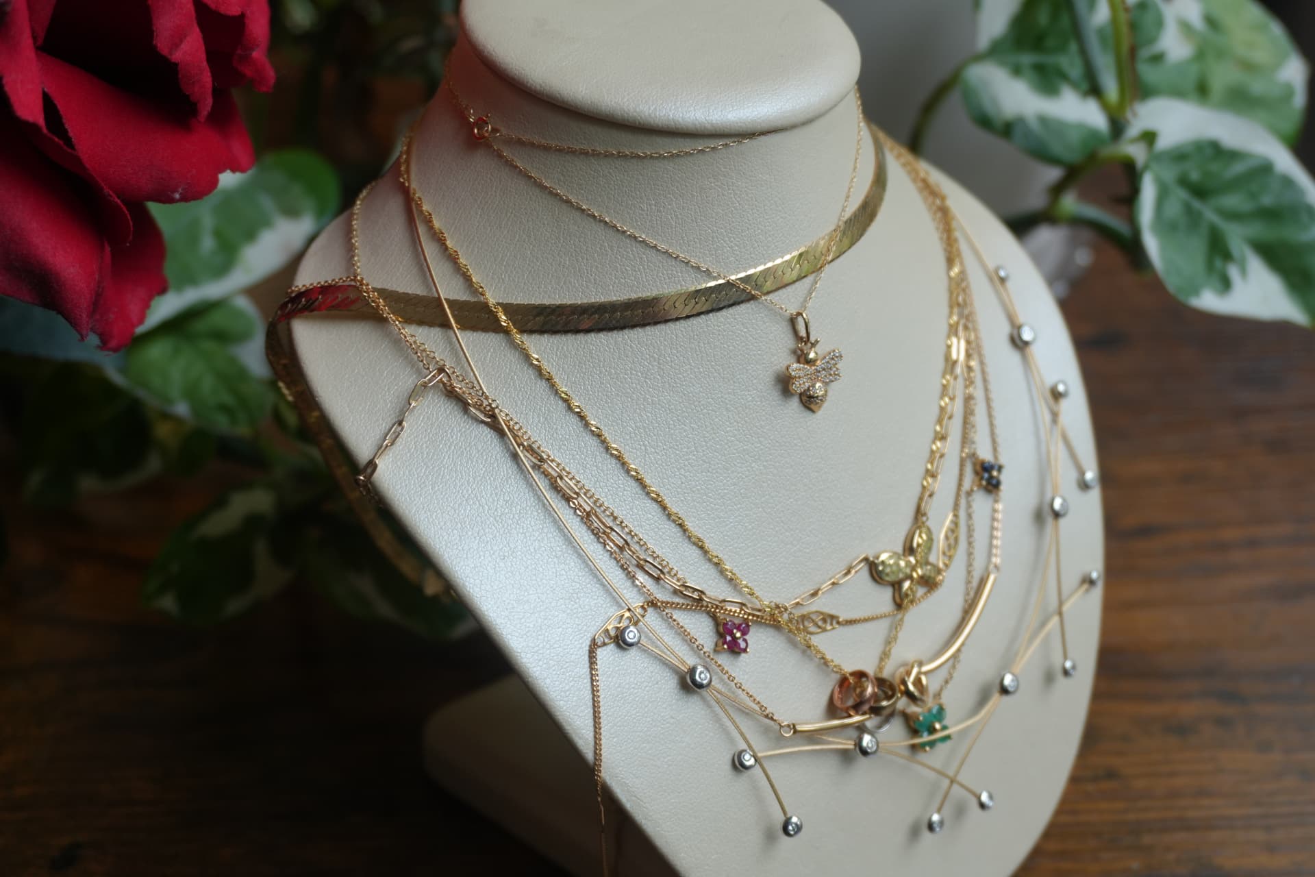 Delicate gold chains with bee, flower and butterfly charms on a bust