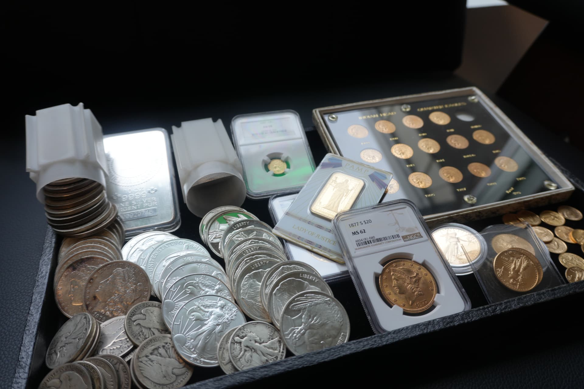 Silver eagles, Morgan dollars and gold coins in a display tray